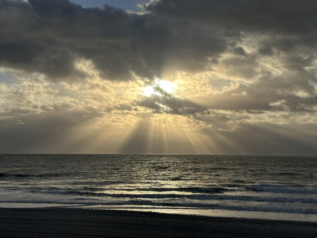 Sun rays breaking through clouds over the ocean