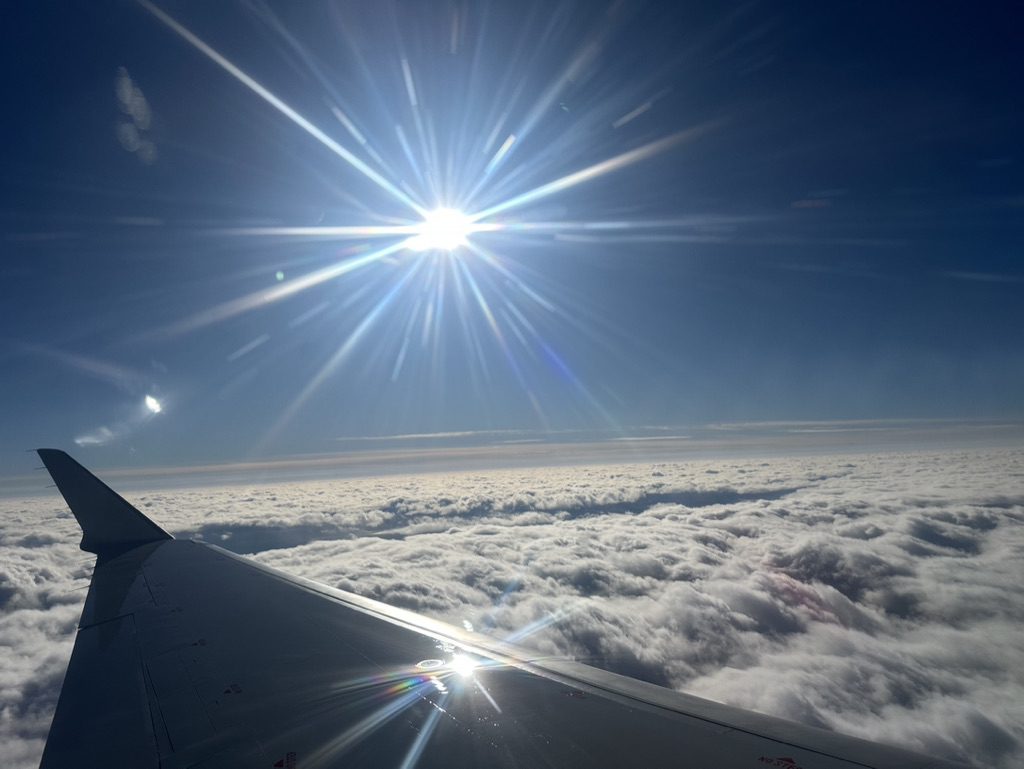 Sun shining over clouds seen from an airplane window